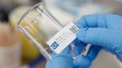 Una persona coloca una etiqueta con código QR en un vaso de precipitados.