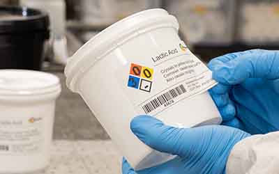 Un químico aplica una etiqueta GHS en un contenedor.