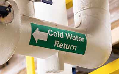 Una etiqueta en una tubería que dice "Cold Water Return."