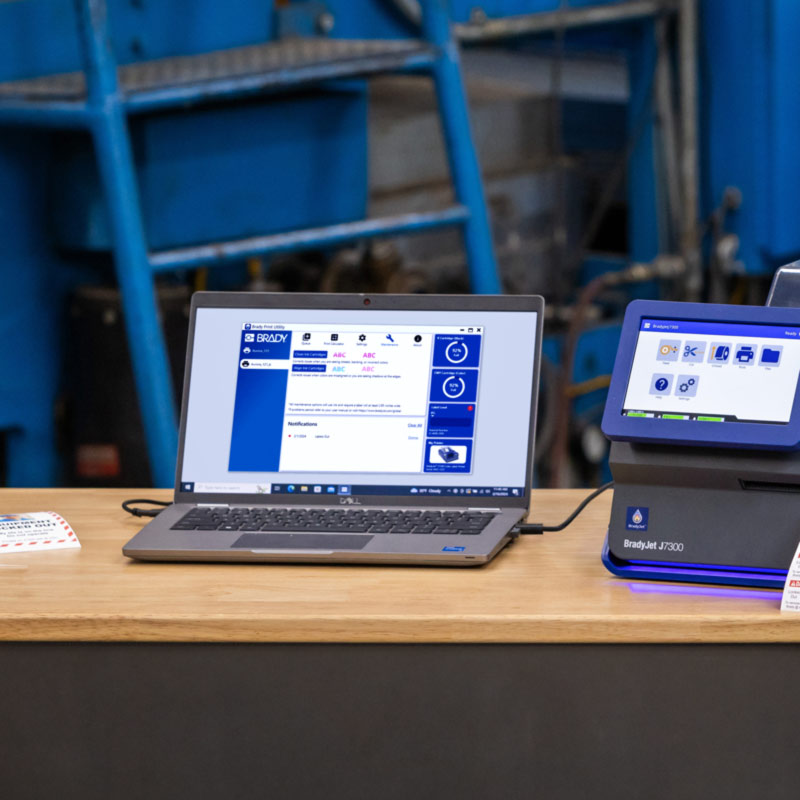 Una laptop conectada a una J7300 muestra una pantalla de Brady Workstation.