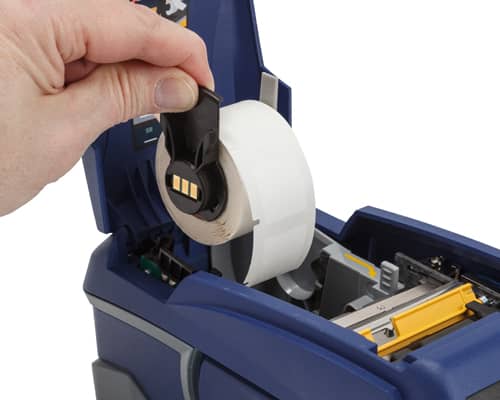 Una persona cargando etiquetas M611 con tecnología de chip inteligente en su impresora M611