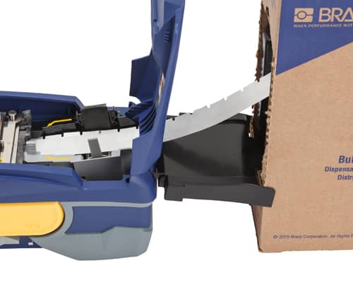 Una impresora Brady M611 con una caje de etiquetas a granel siendo alimentada en la impresora