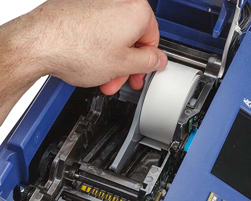 Un rollo de material de etiqueta siendo cargado en una impresora M710.