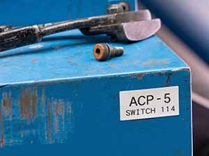 Una máquina azul con una etiqueta con el nombre 'ACP-5 SWITCH 114'