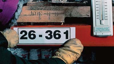 Una persona que usa guantes aplica una etiqueta dentro de un congelador.