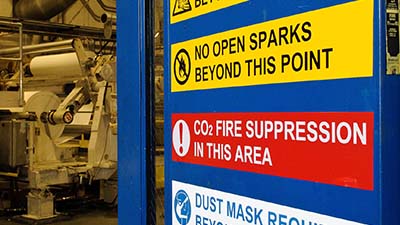Etiquetas de advertencia en la puerta de una planta de manufactura.