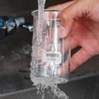 Un matraz de vidrio con una etiqueta disoluble Brady que se está limpiando y al que se le está quitando la etiqueta.