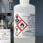 Un contenedor de etanol con una etiqueta de seguridad GHS que identifica su contenido.