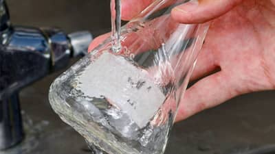 Un matraz de vidrio con una etiqueta disoluble Brady que se está limpiando y al que se le está quitando la etiqueta.