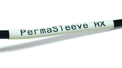 Un alambre negro con una etiqueta PermaSleeve termocontráctil de color blanco aplicada sobre él.