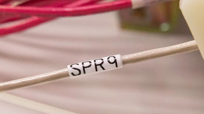 Un alambre de color café con una etiqueta de identificación blanca dentro de un arnés de cableado.