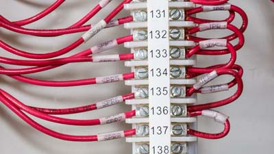 Una serie de alambres rojos dentro de un bloque de terminales identificados con una etiqueta de bloque de terminales blanca.