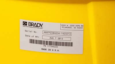 Una etiqueta de poliéster metalizado brillante de Brady aplicada a la superficie curva de un recipiente más grande.