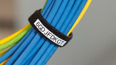 Etiquetas con gancho Bradygrip envueltas alrededor, asegurando e identificando un grupo de cables de datos.