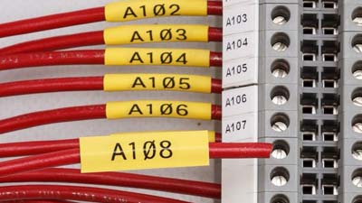 Seis mangas termocontráctiles de color amarillo con el texto A102, A103 a A108 impreso en cada una, todas conectadas a un panel de circuito.