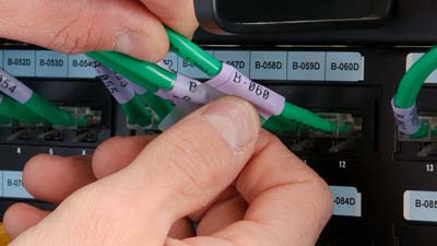 Una etiqueta envolvente de vinilo autolaminable que se envuelve alrededor de un cable Cat-5e verde.