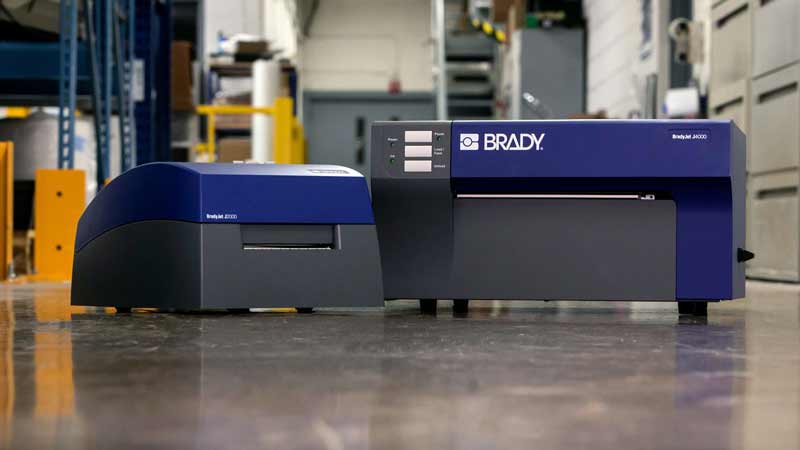 Dos impresoras de inyección de tinta Brady en un piso de concreto de un almacén.0