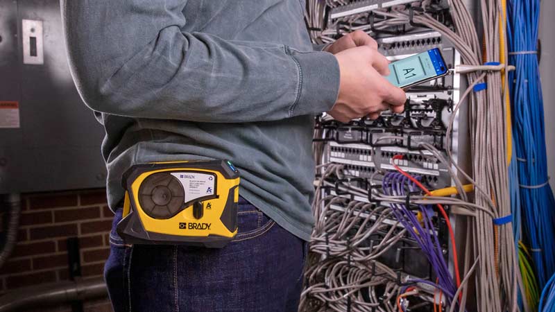 Un trabajador hace una etiqueta para cables en una aplicación para una impresora portátil de etiquetas en un cuarto de servidores.